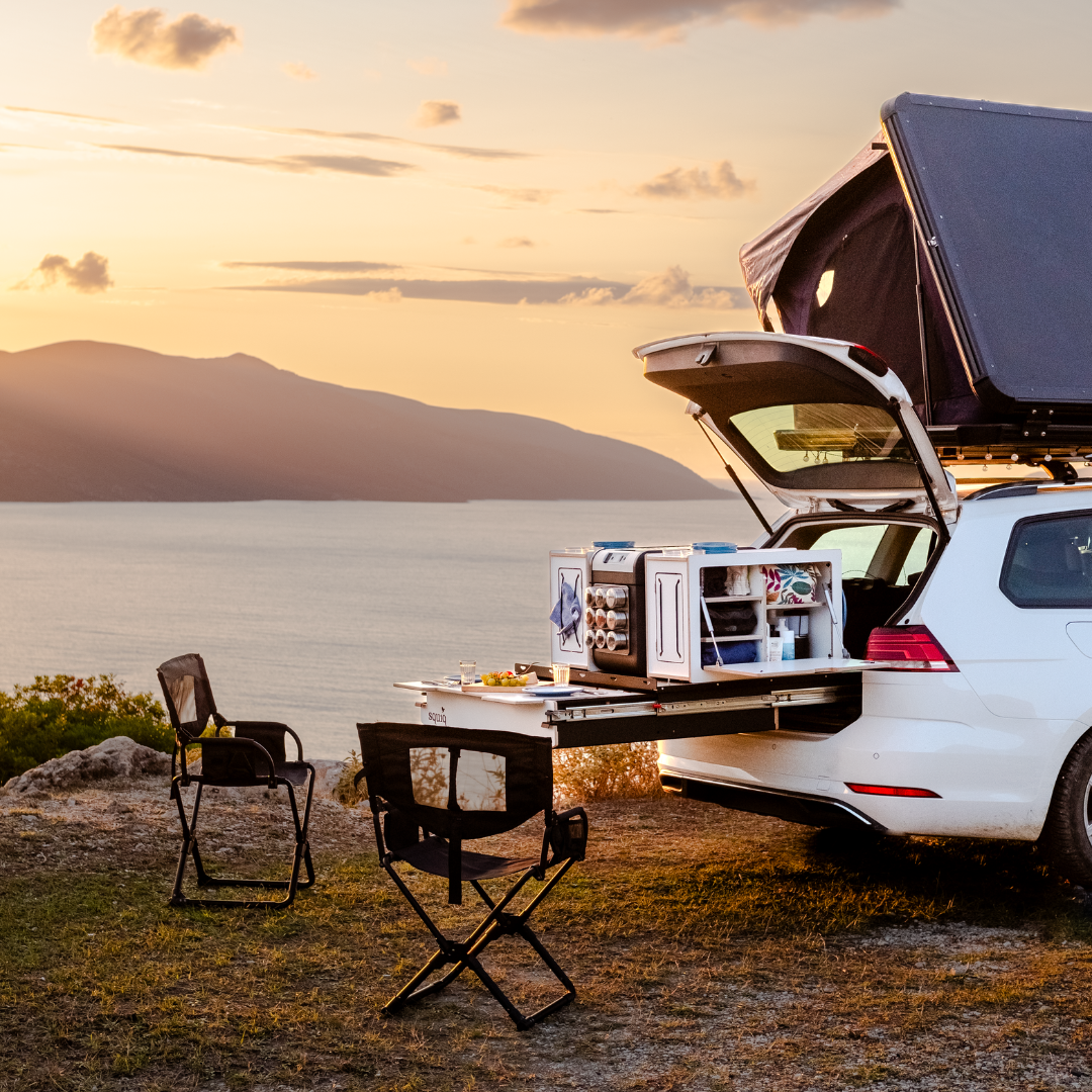 squiq Traveler Heckauszug mit modularen Campingboxen im Kombi mit Dachzelt bei Sonnenuntergang mit Esstisch und Stühlen