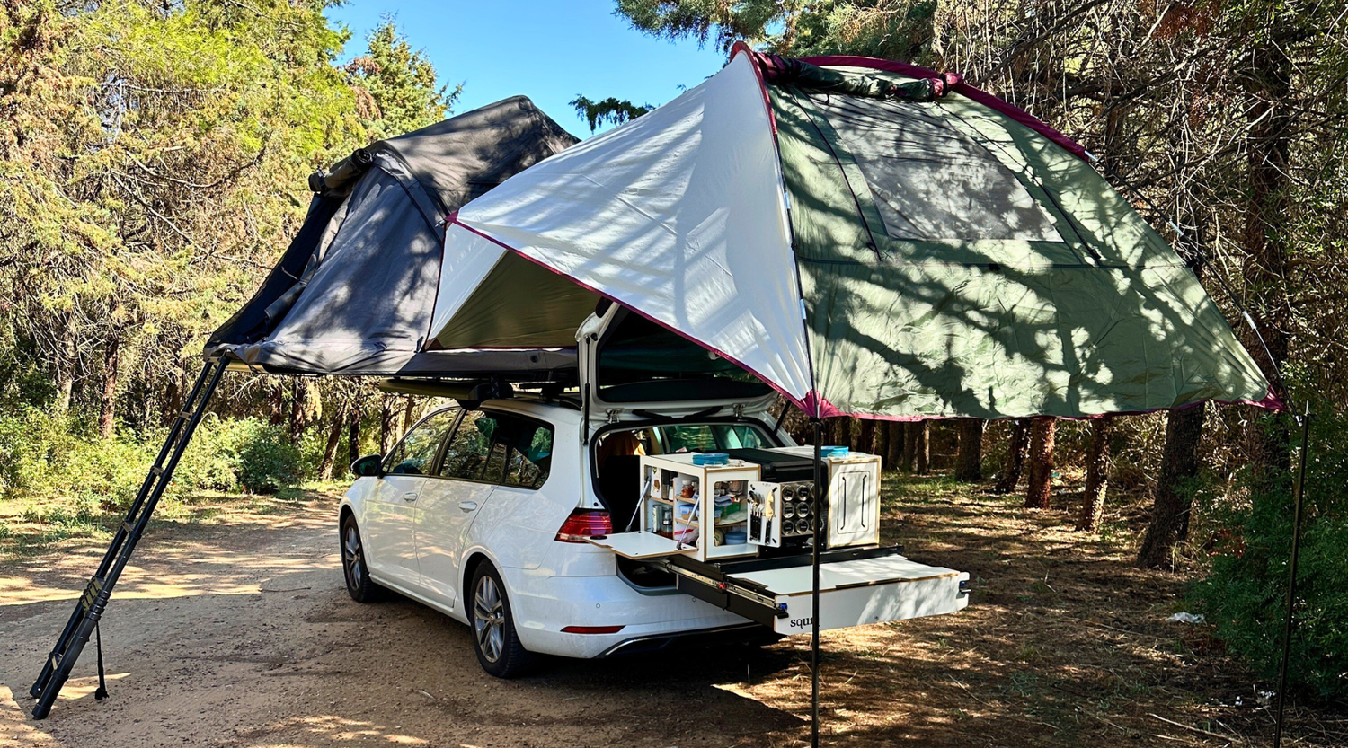 Auto mit Dachzelt und Heckzelt über dem Heckauszug mit modularen Campingboxen im Wald 