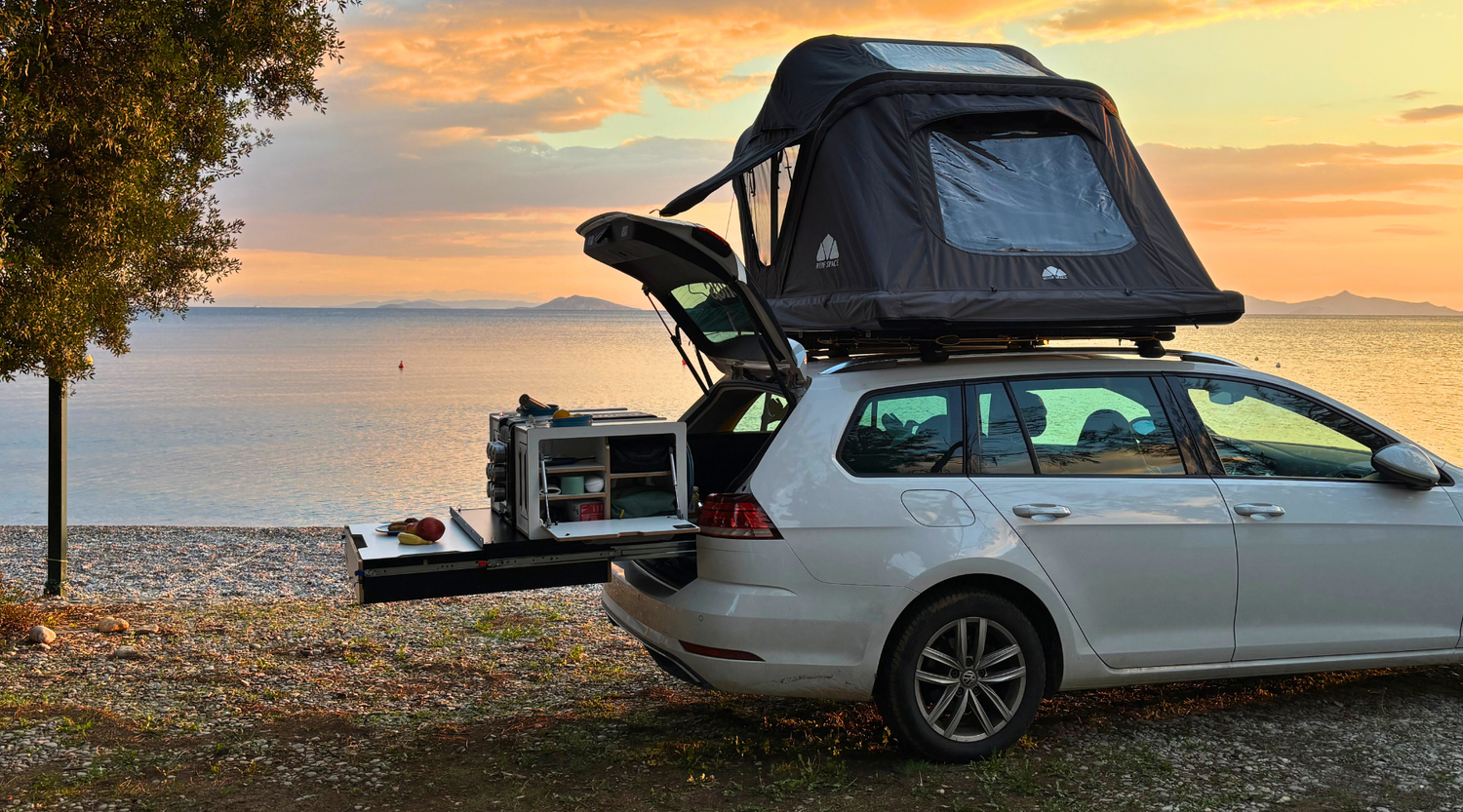 Dachzelt Camping als echte Alternative zum Campervan mit Heckauszug in einem Kombi beim Sonnenuntergang am Meer