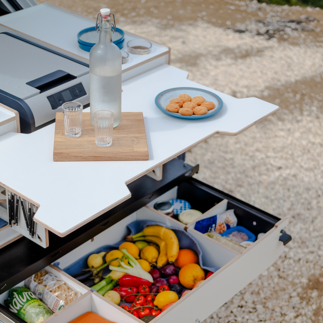Campingbox voor de auto met uitgeschoven tafel, levensmiddelen en koelbox tijdens het camperen met de auto