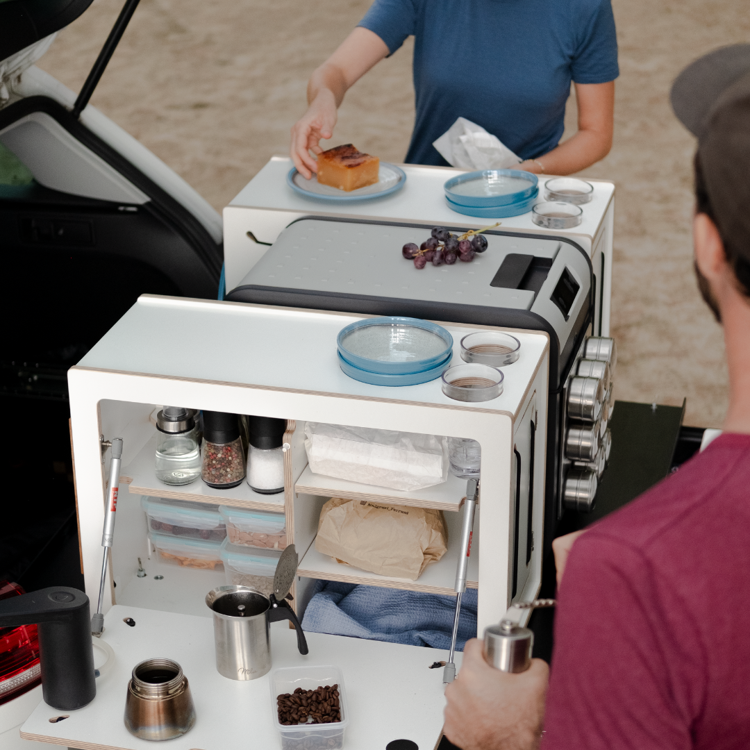 Camping-System im Auto mit zwei Personen beim Kaffeezubereiten