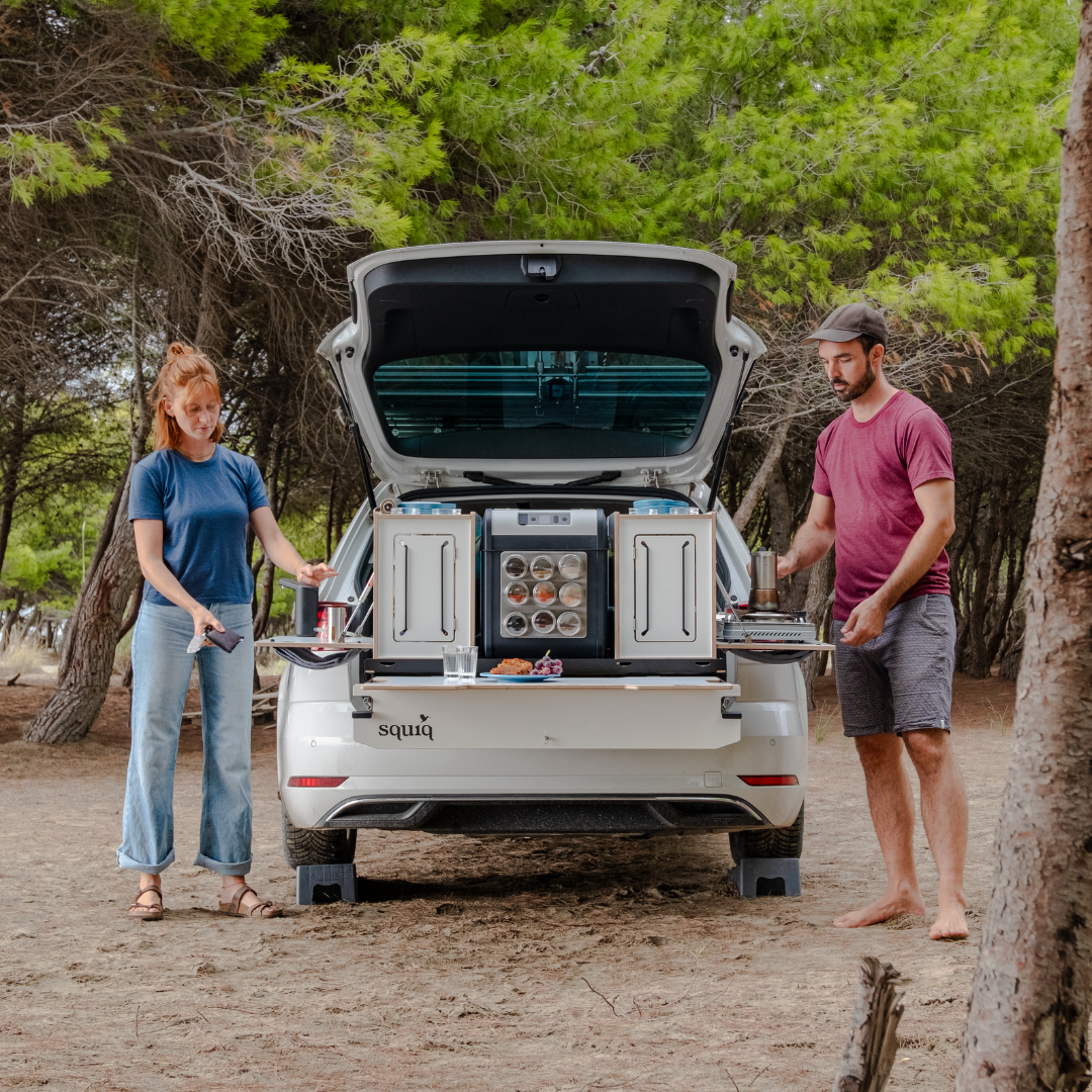 Zwei Personen am Mini-Camper mit Campingbox-Modulen beim Abwaschen und Kochen